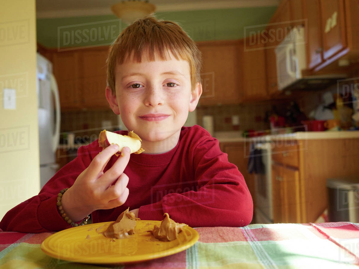 Caucasian boy eating apple with peanut butter snack Stock Photo