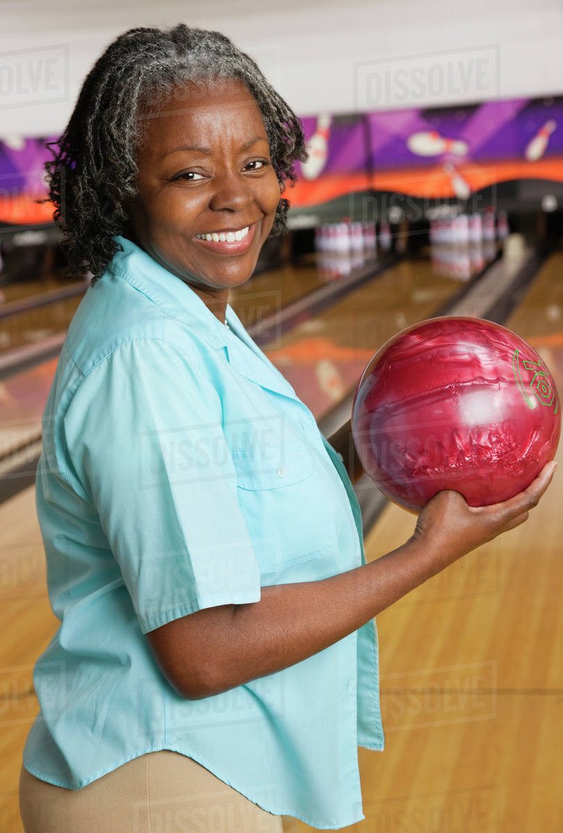 African woman holding bowling ball Stock Photo Dissolve