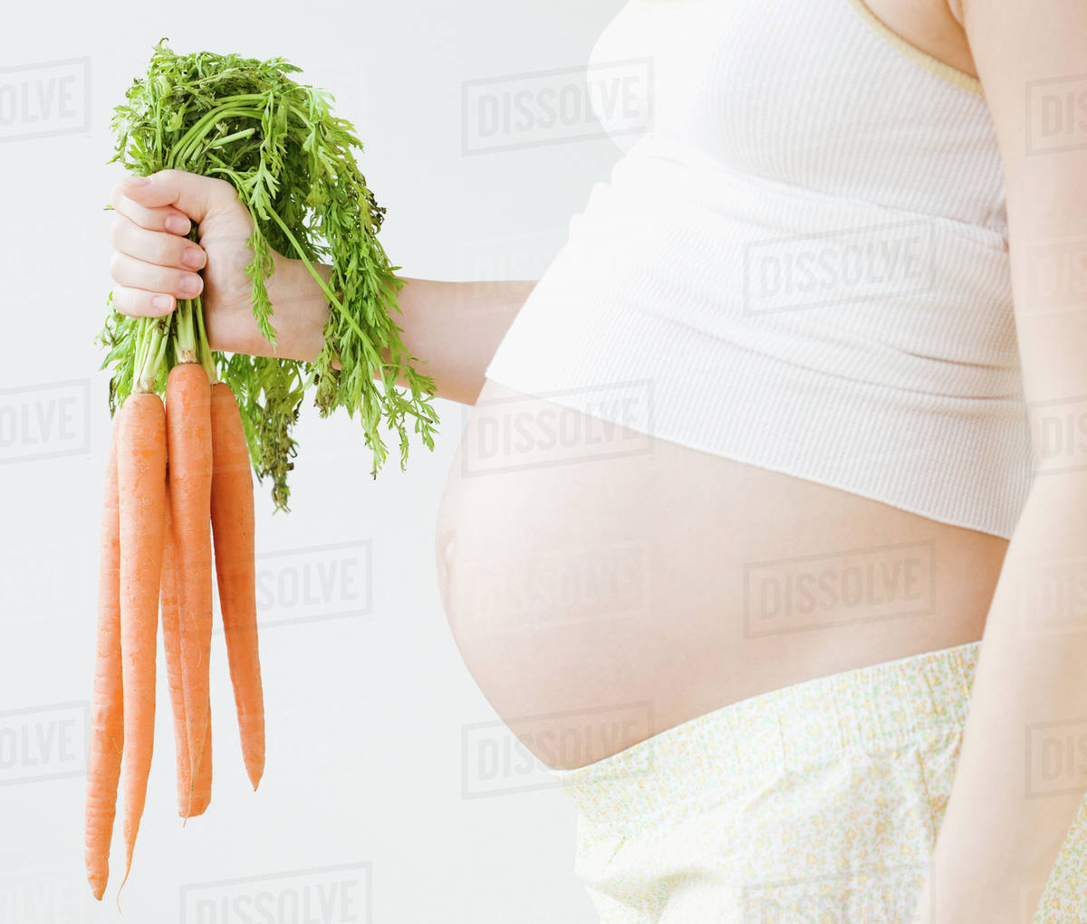 Pregnant Asian woman holding bunch of carrots Stock Photo Dissolve