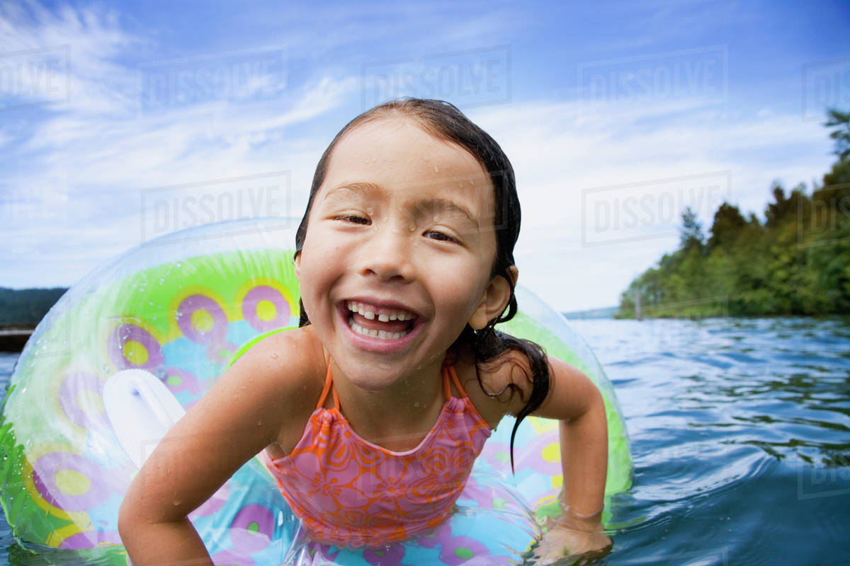 Asian girl swimming with inner tube Stock Photo Dissolve