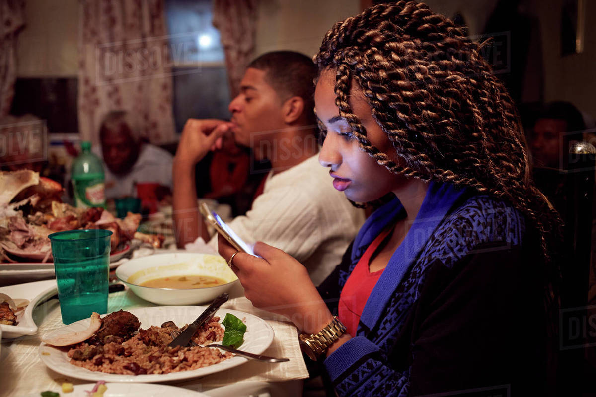 Teenage girl using cell phone at dinner table - Royalty-free Stock ...