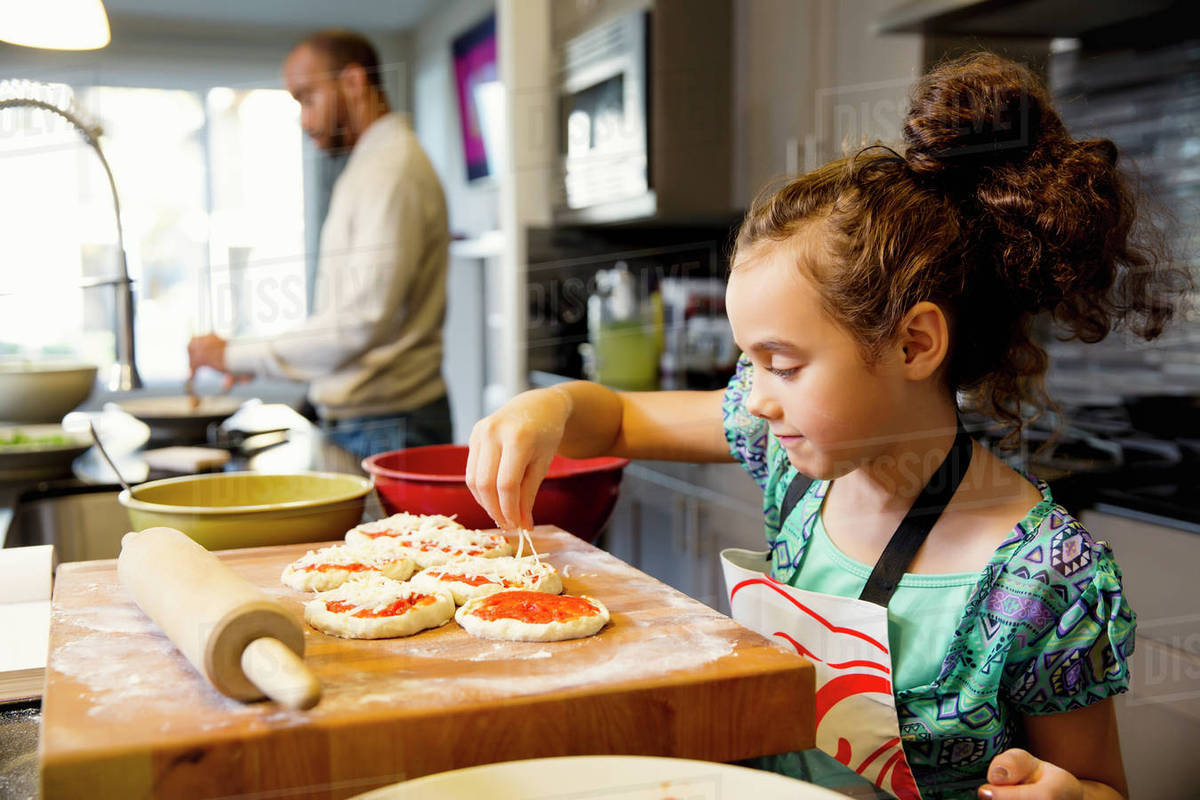 Mixed race girl cooking in kitchen Stock Photo Dissolve