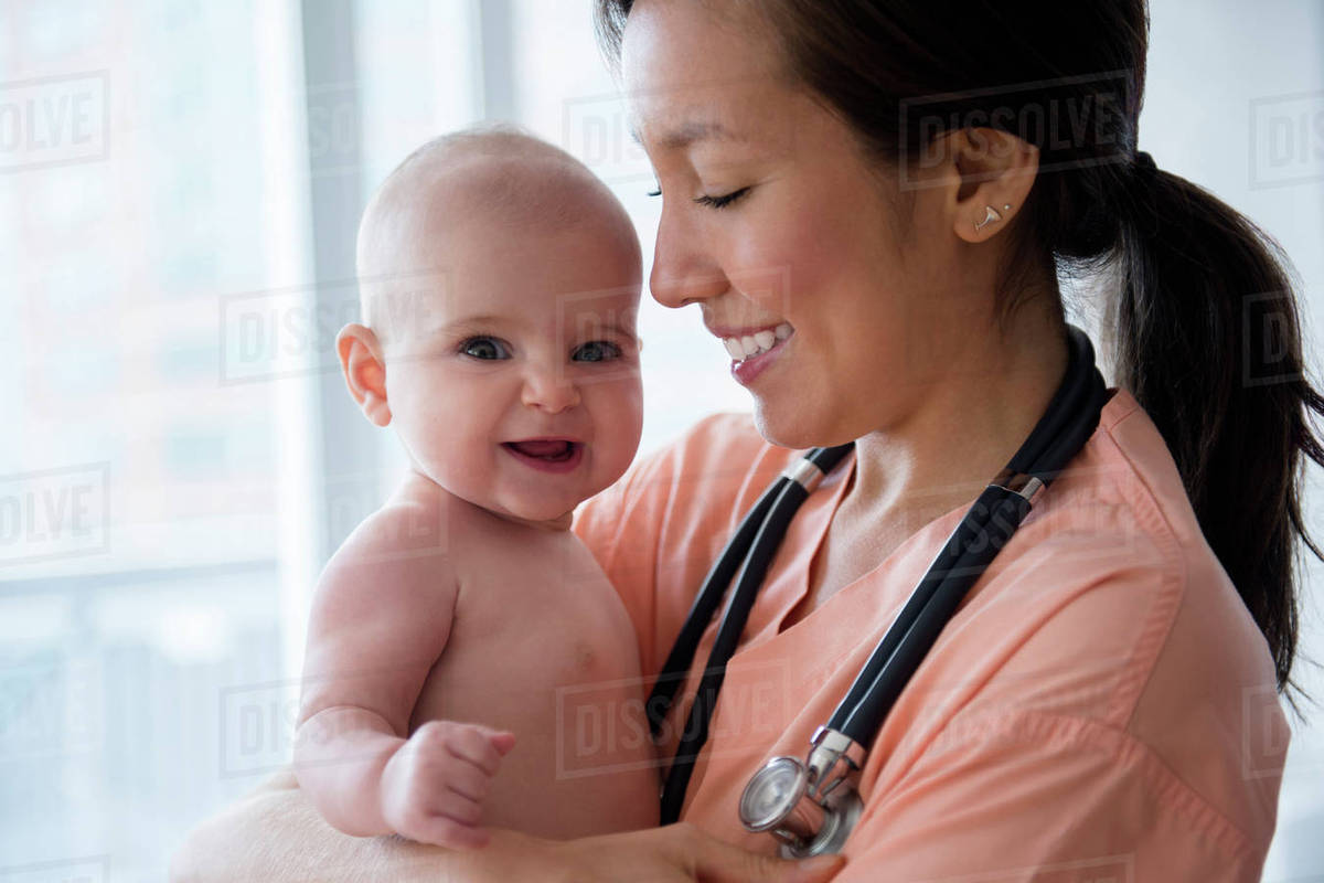 Nurse holding baby girl in hospital Stock Photo Dissolve