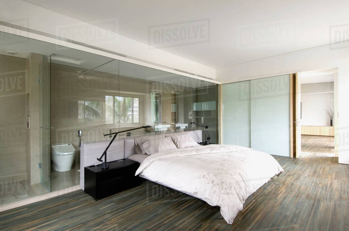 Modern bedroom with glass wall through to bathroom Stock Photo Dissolve