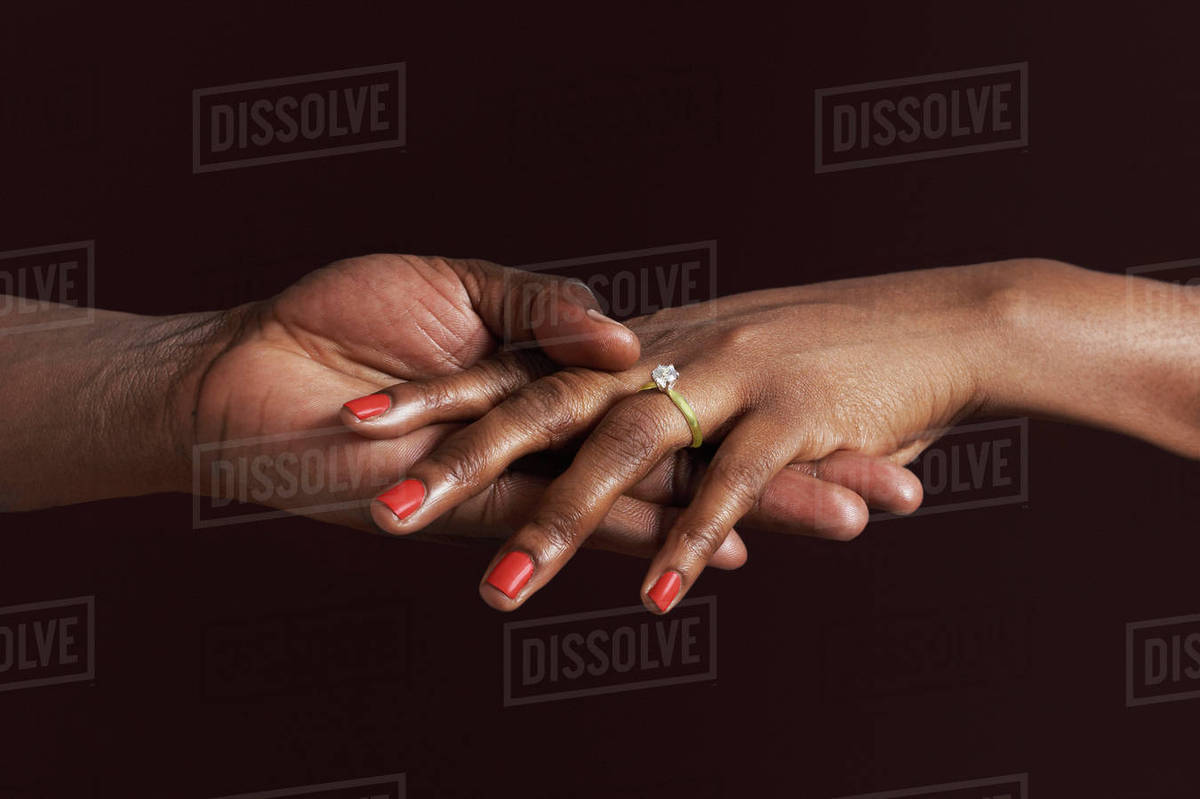 African woman with engagement ring holding fiancee's hand Stock Photo