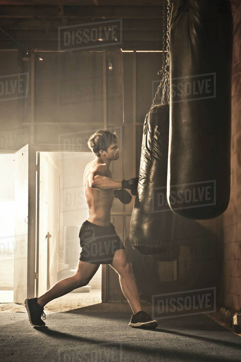 Caucasian boxer hitting punching bag Stock Photo Dissolve
