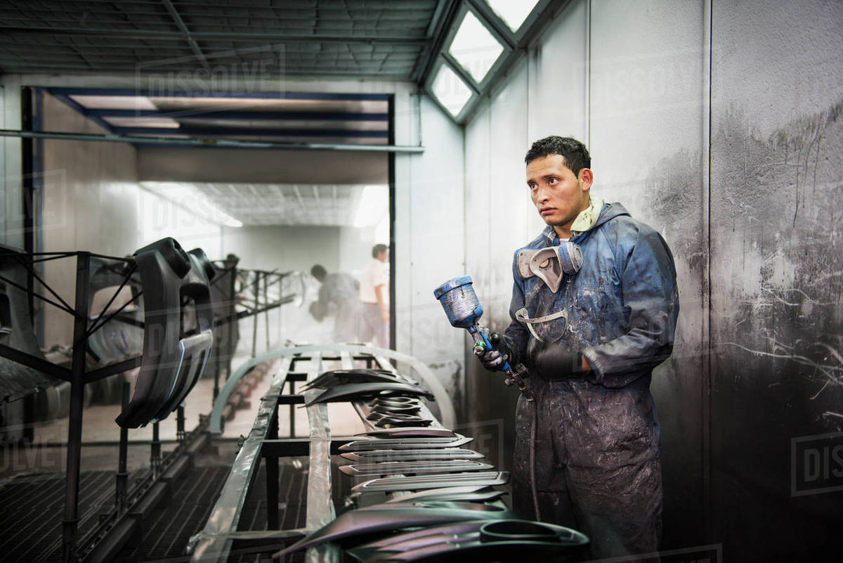 Worker spray painting in manufacturing plant Stock Photo Dissolve