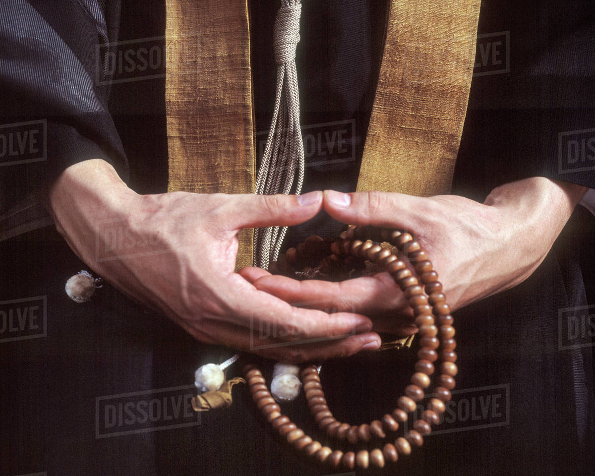 Close up of hands holding Buddhist prayer beads Stock Photo Dissolve