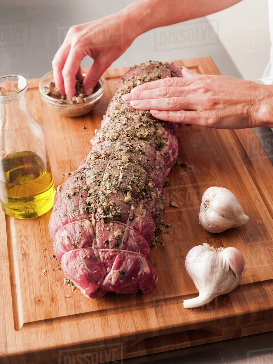 Hands rubbing garlic and pepper onto tenderloin Stock Photo Dissolve