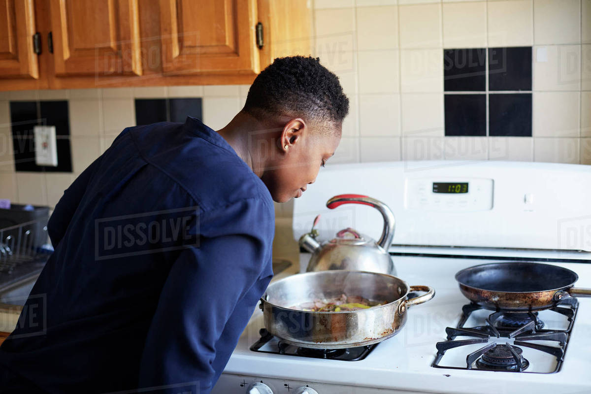 Woman smelling food cooking in pan on stove Stock Photo Dissolve