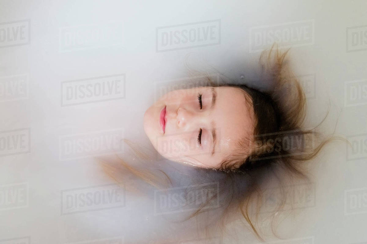 Face of Caucasian girl floating in bathtub Stock Photo Dissolve
