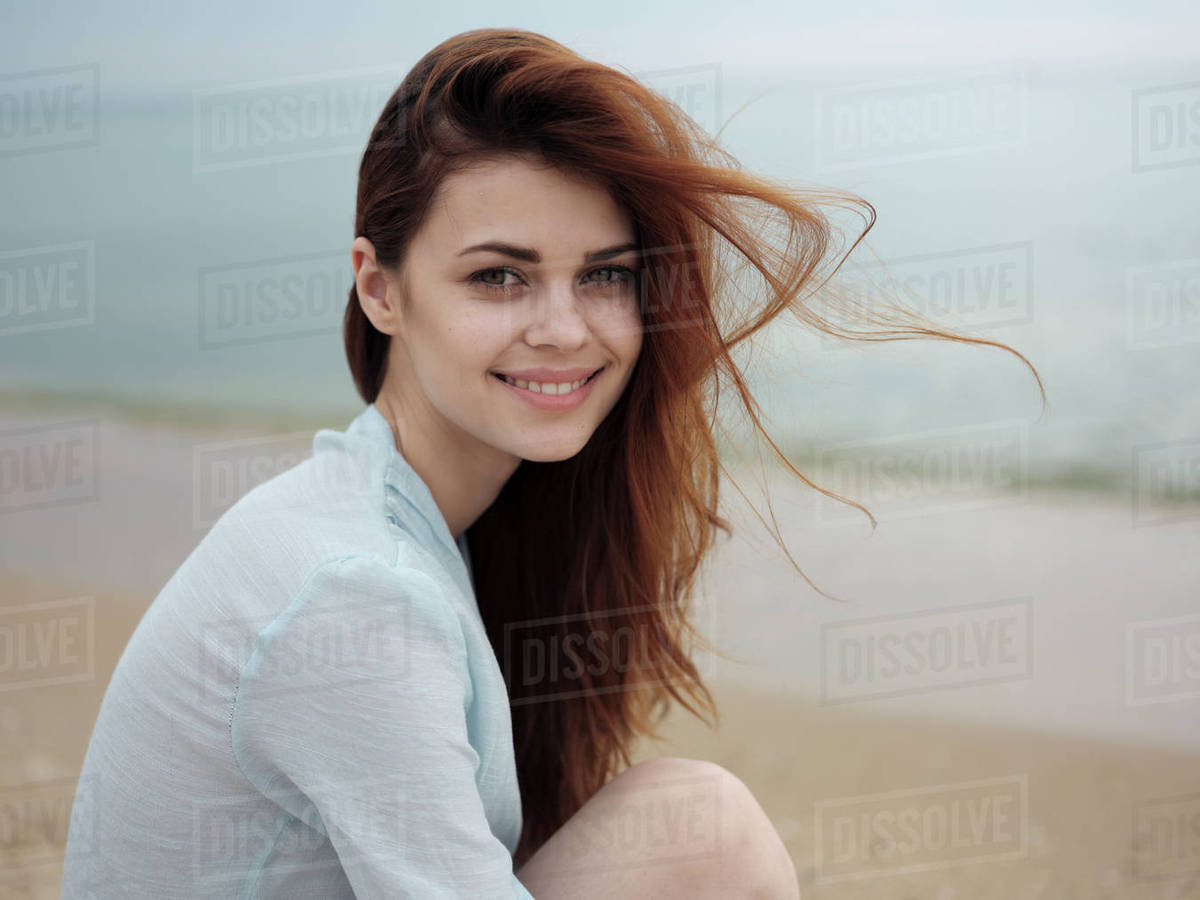 wind blowing hair of caucasian woman sitting on the beach stock