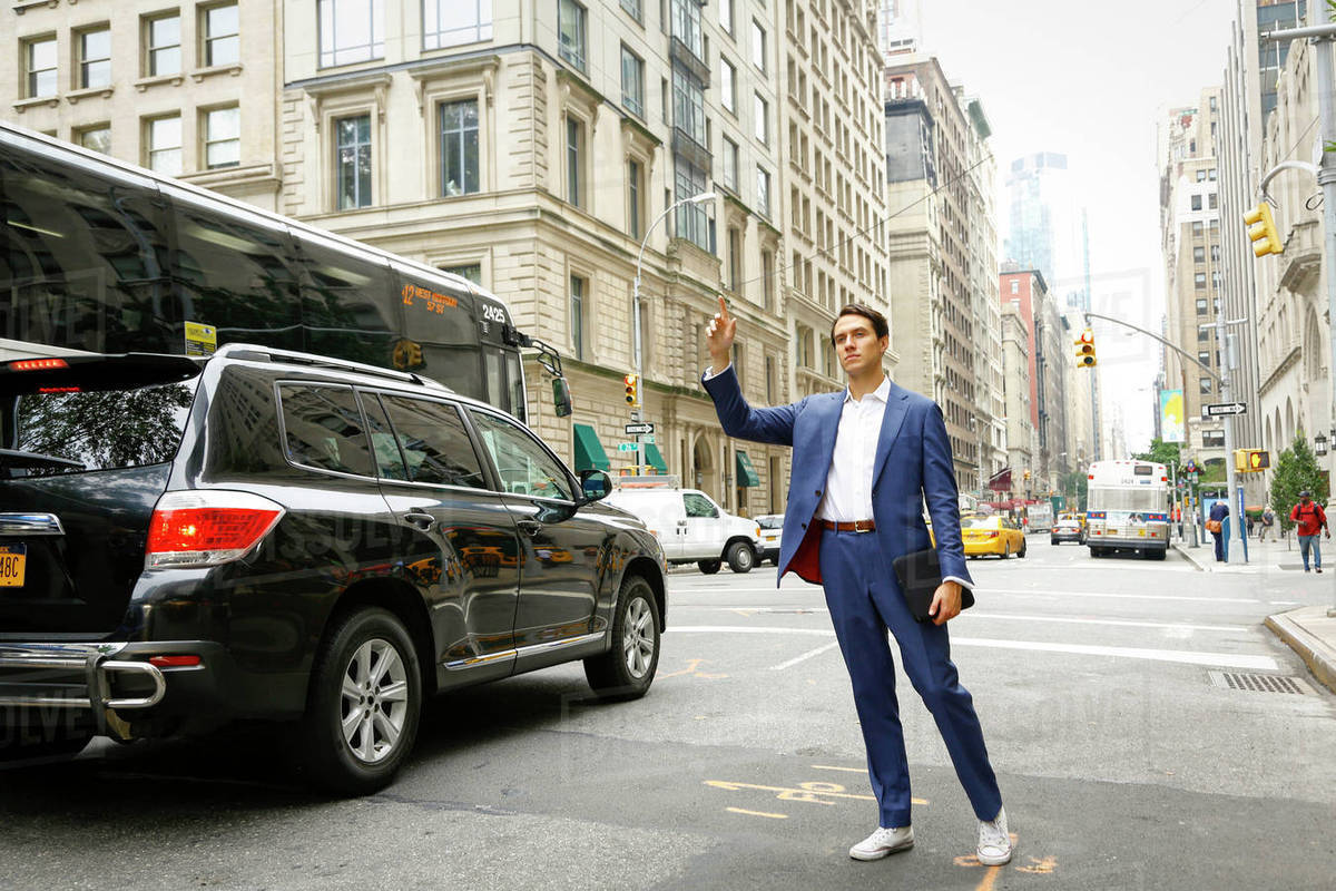 Caucasian businessman standing in street hailing taxi Stock Photo