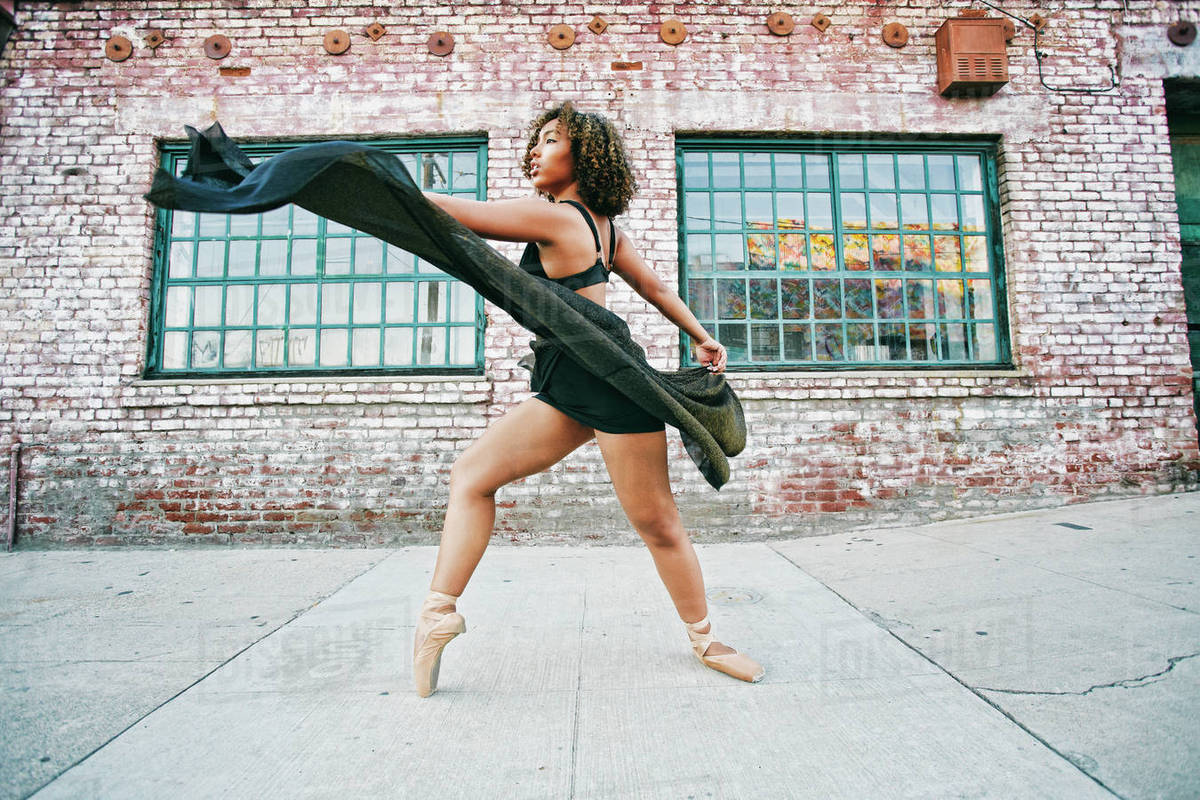 Mixed race woman dancing ballet on sidewalk Stock Photo Dissolve