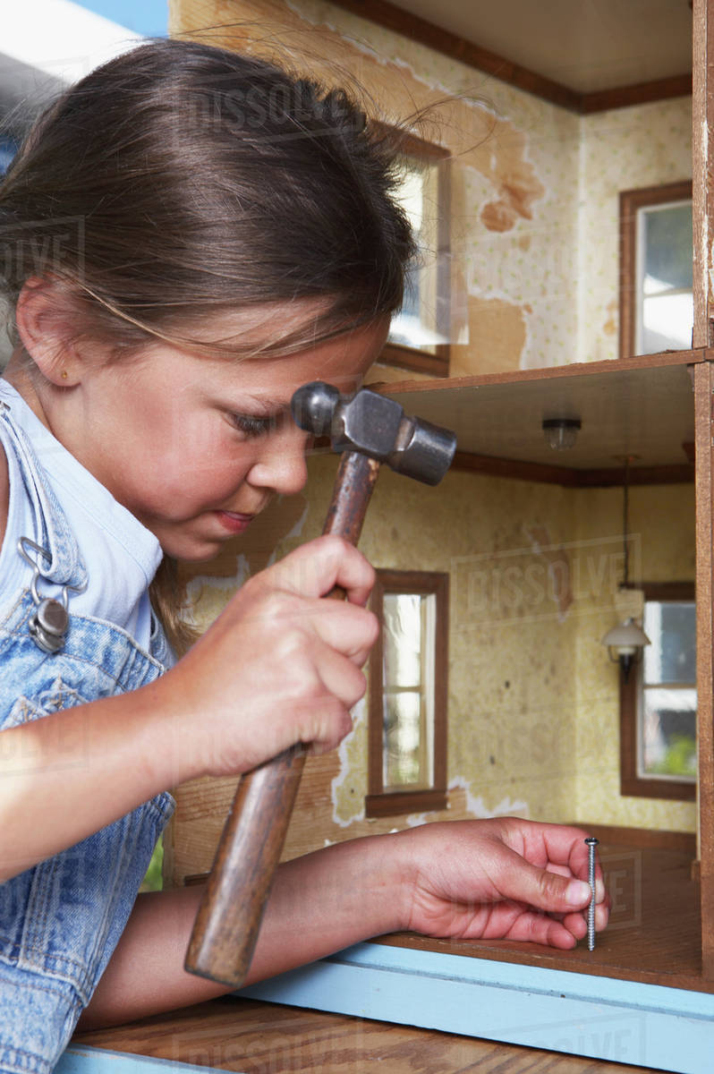 Mixed race girl fixing doll house Stock Photo Dissolve