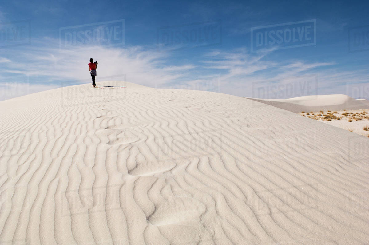 Man climbing sand dune in desert Stock Photo Dissolve