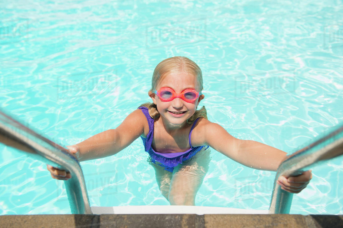 Caucasian girl climbing out of swimming pool Stock Photo Dissolve