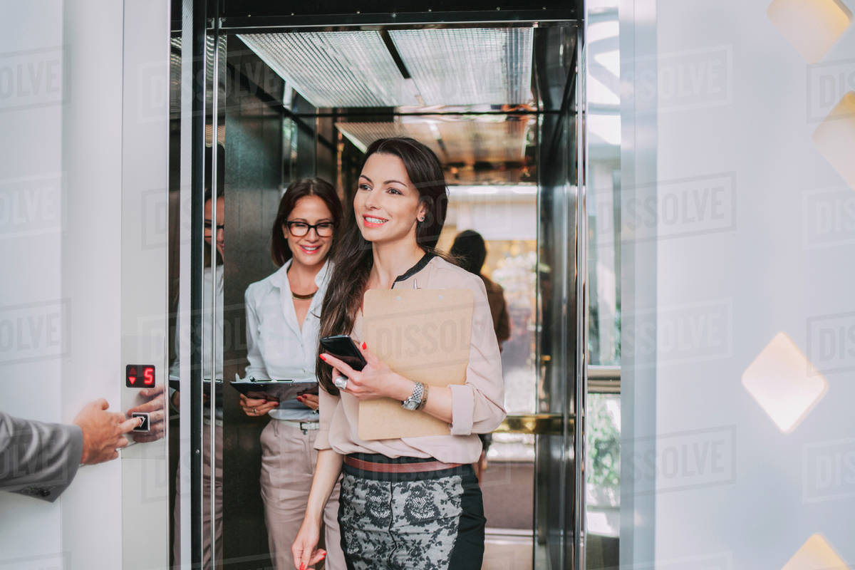 Caucasian businesswomen walking out of elevator Stock Photo Dissolve