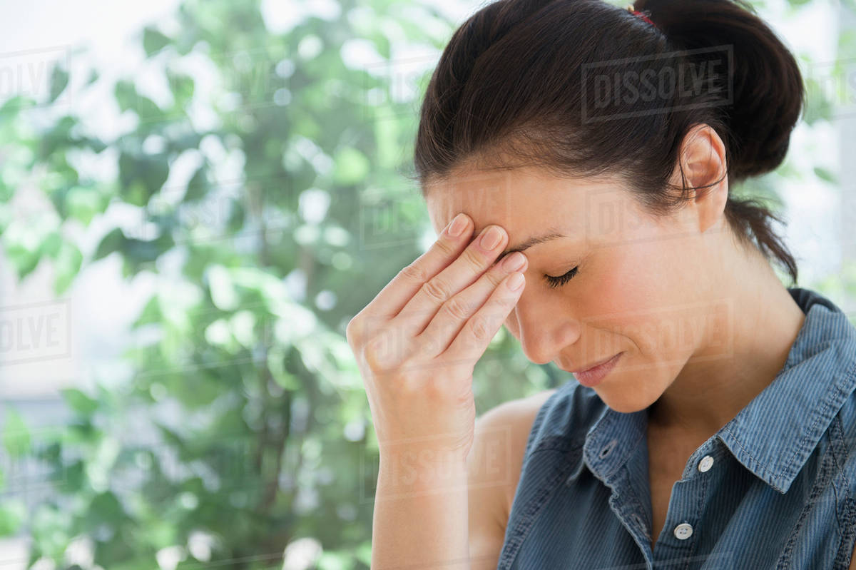 Caucasian woman rubbing her forehead Stock Photo Dissolve