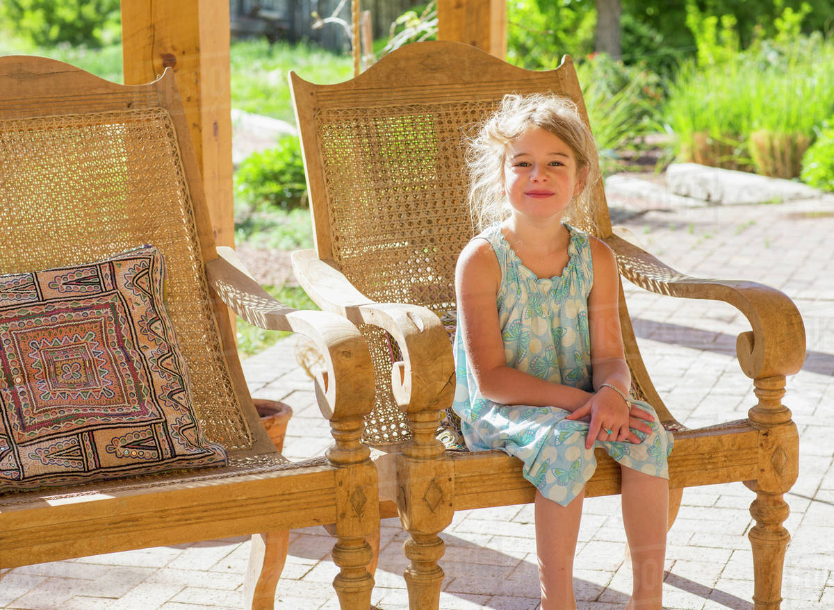 Caucasian girl sitting on patio Stock Photo Dissolve