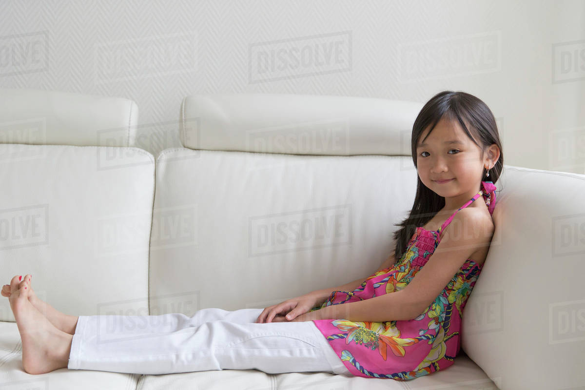 Asian girl relaxing on sofa Stock Photo Dissolve