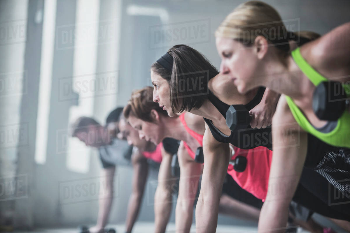 Athletes doing pushups and lifting weights on floor Stock Photo
