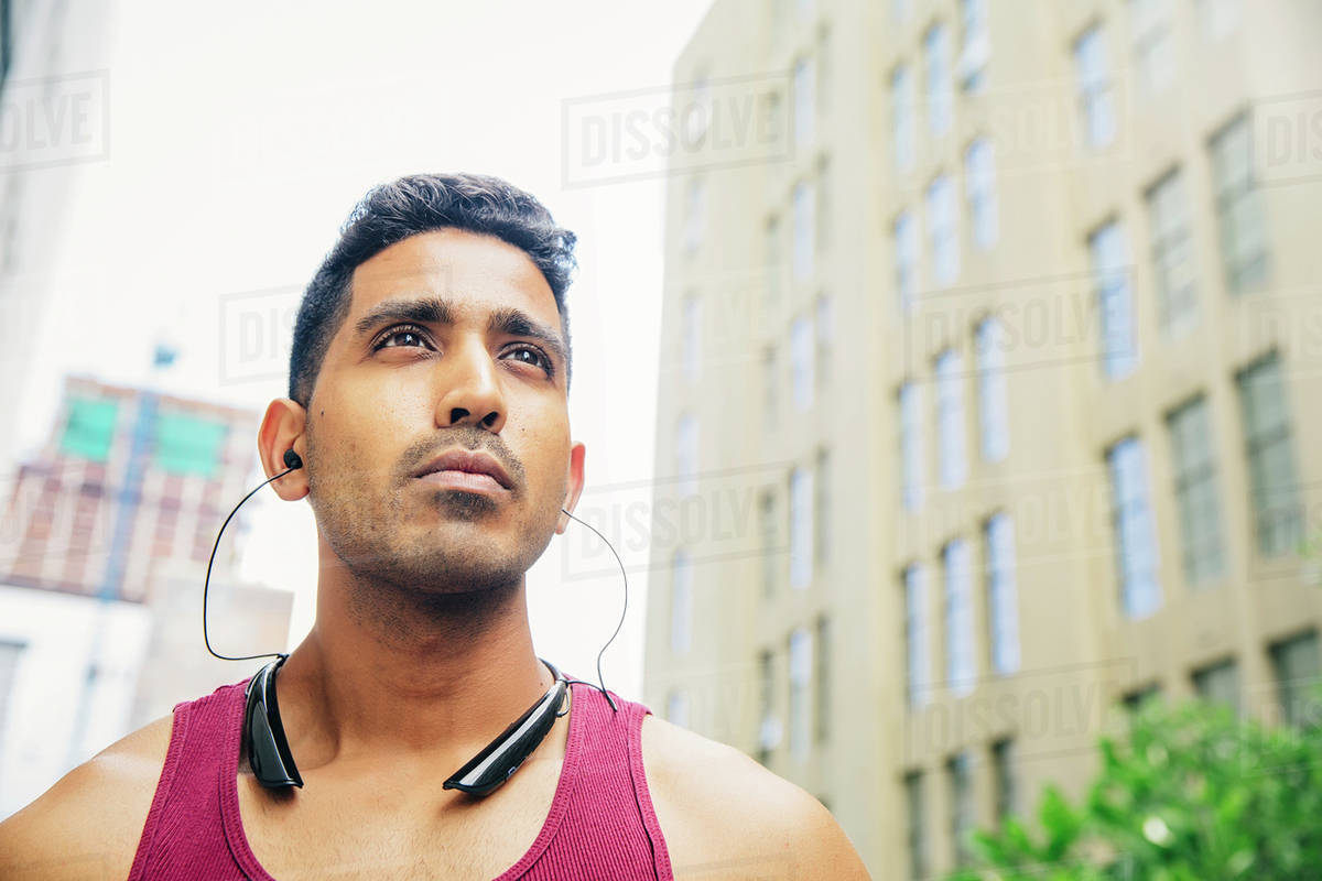 Indian athlete listening to earbuds in city Stock Photo Dissolve