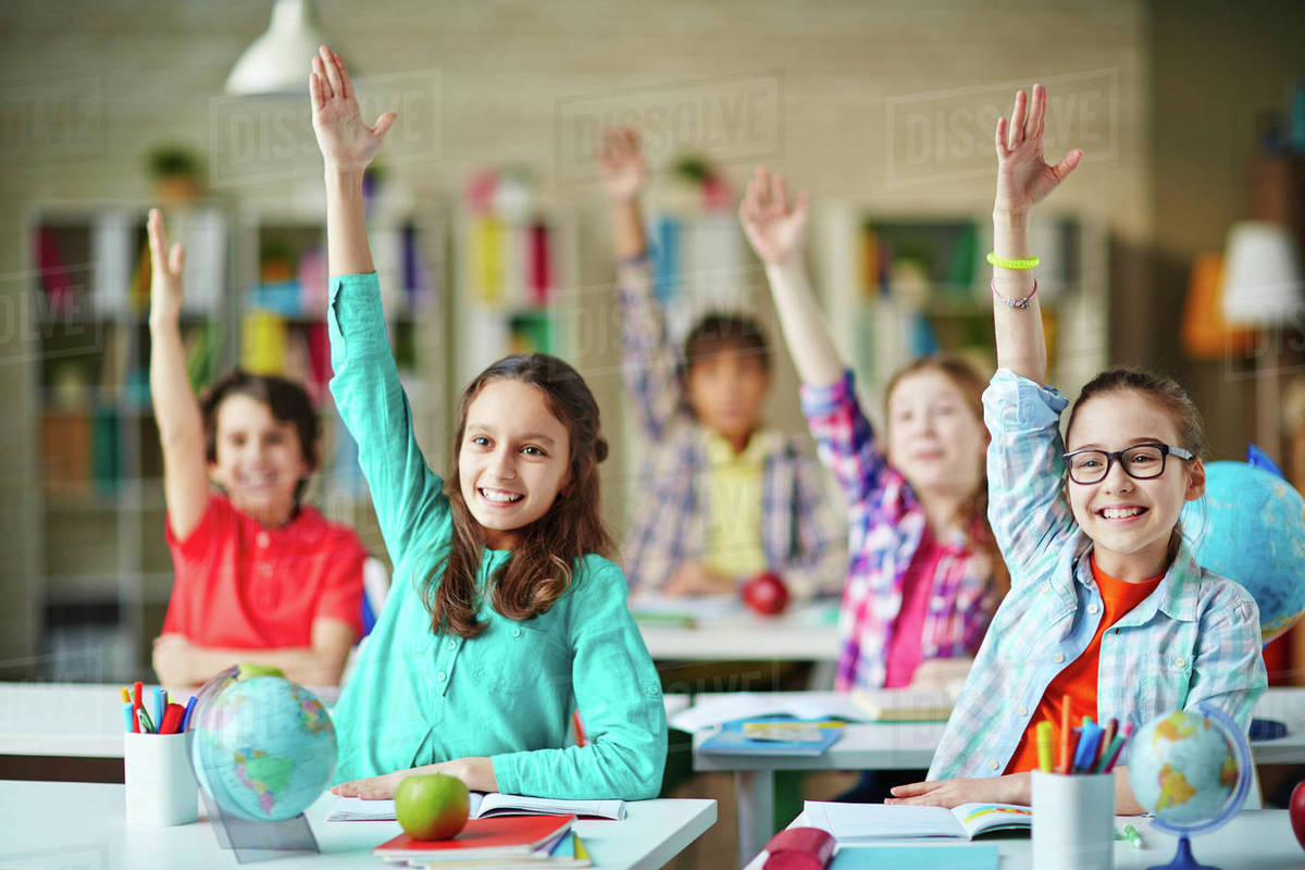 Clever girls and boys raising hands to answer the question Stock