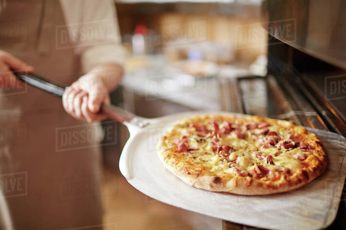 Freshly Cooked Delicious Pizza Held By Chef Stock Photo Dissolve
