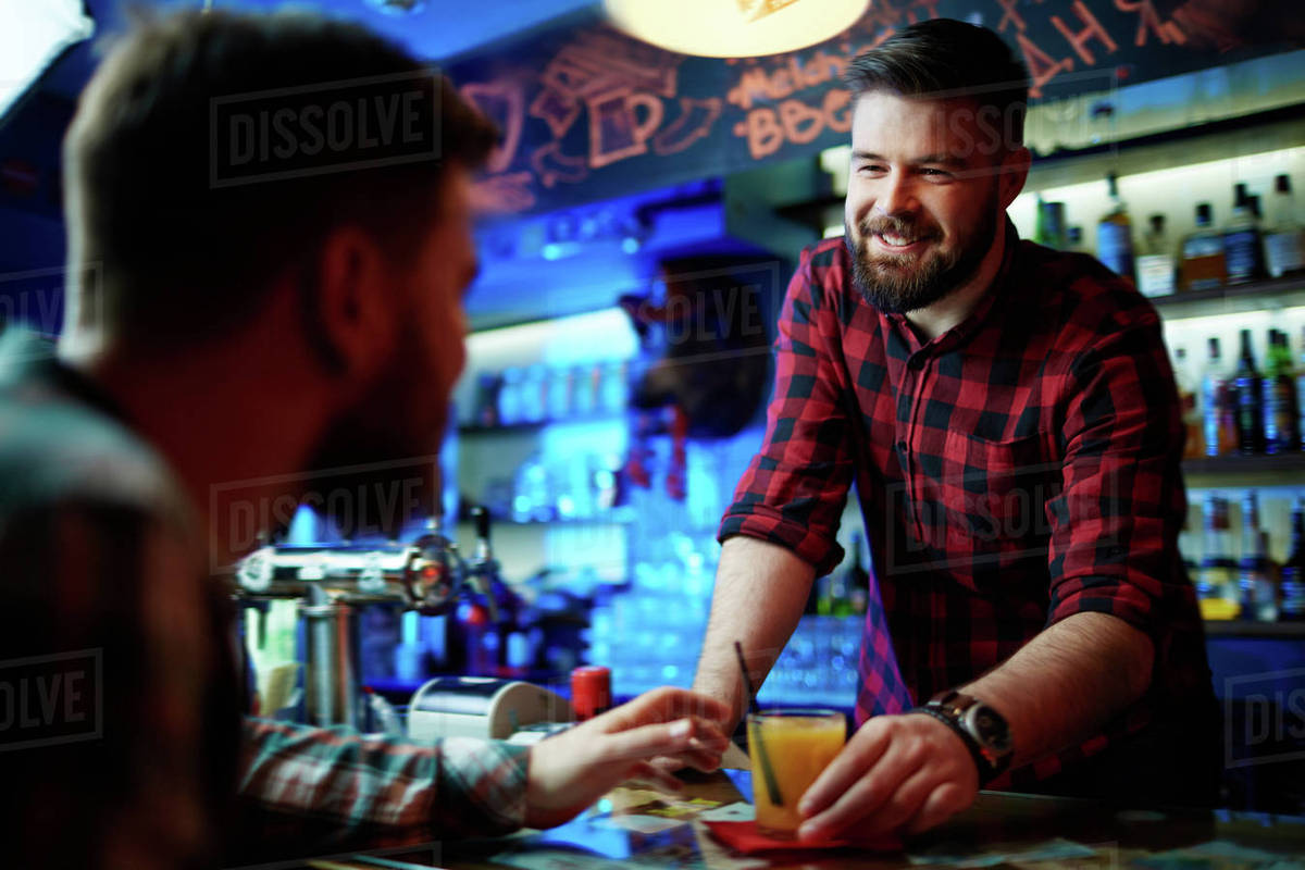 Bartender flirting with customer and giving him a cocktail Stock