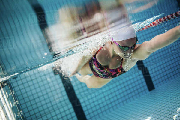 Underwater shot of young woman swimming in pool. Female swimmer inside ...