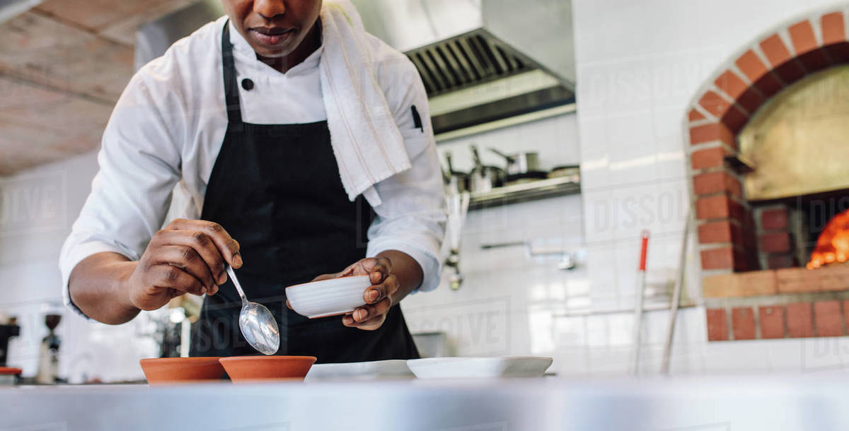 Chef in apron doing food preparation on commercial kitchen counter