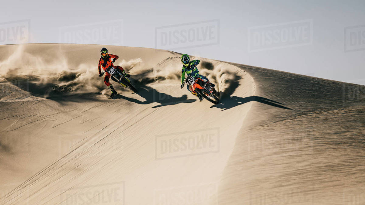 Motocross competition over dunes in desert. Motor bike riders