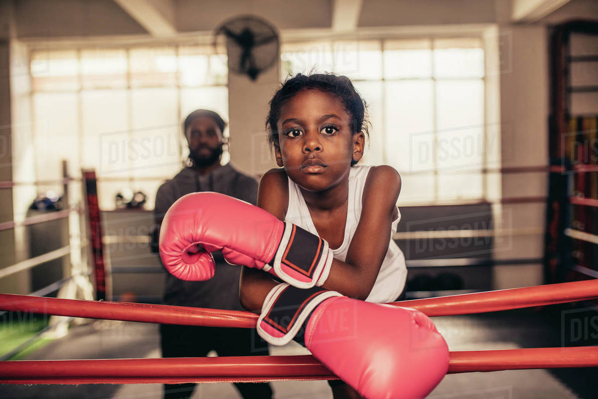Confident looking boxing kid standing inside a boxing ring with her