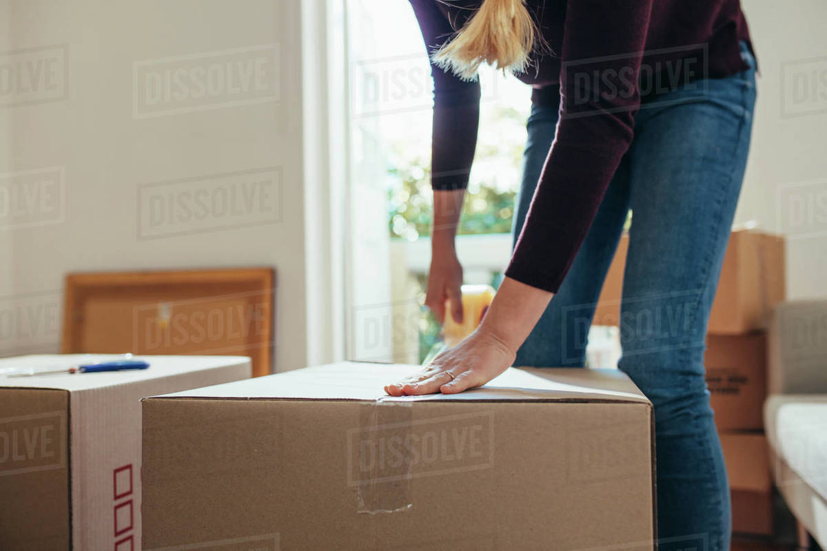 Woman using adhesive tape to seal the packing boxes. Woman moving out