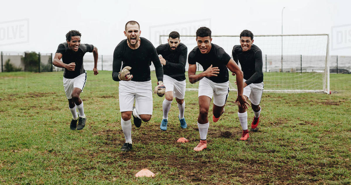 Soccer players running on field shouting in joy after winning the match. Players celebrating