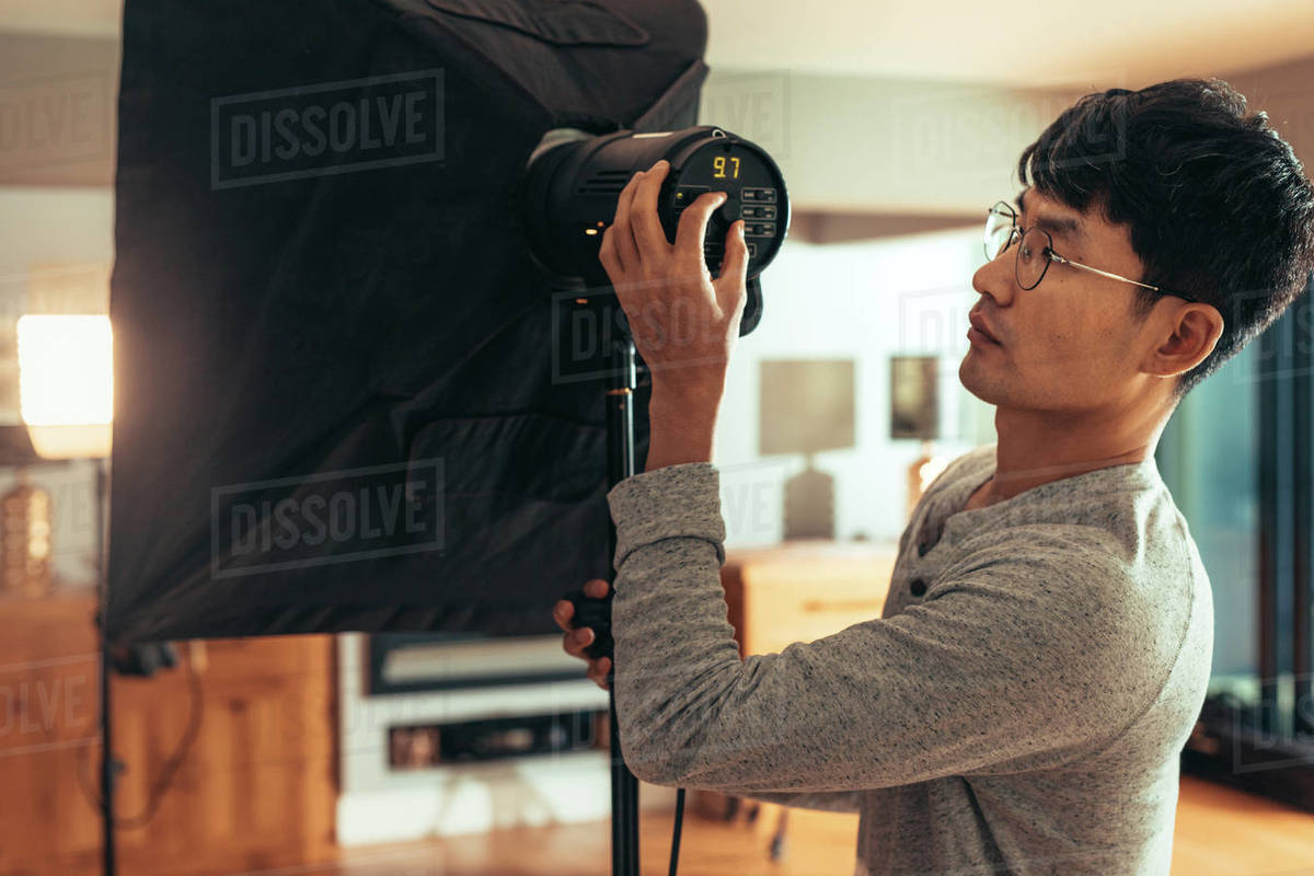 Photographer adjust softbox light intensity in studio. Man setting