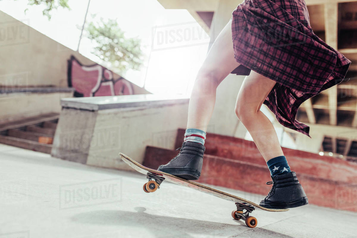 Low angle shot of young woman legs skateboarding at skate park Royalty-free stock photo