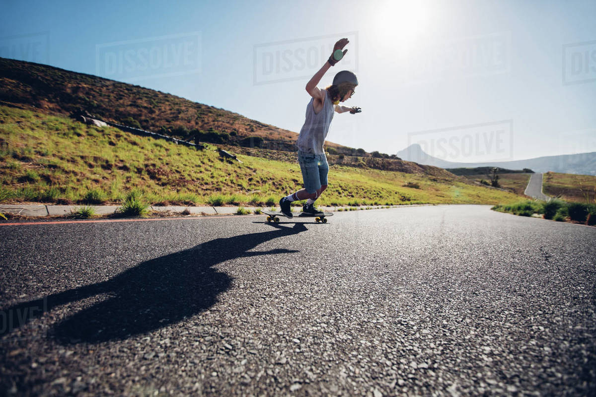 Outdoors shot of young man skateboarding down the road on sunny day. Royalty-free stock photo