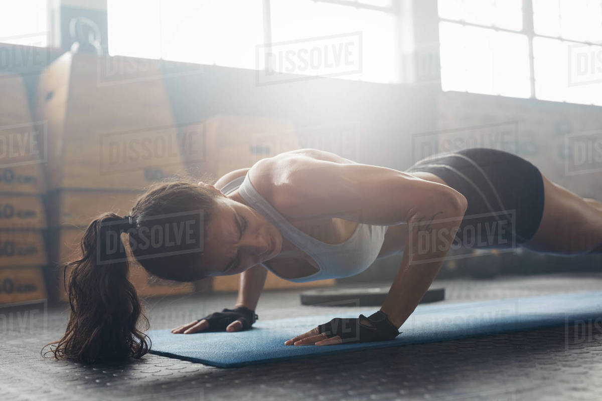 Shot of young woman doing pushups at the gym. Strong female athlete