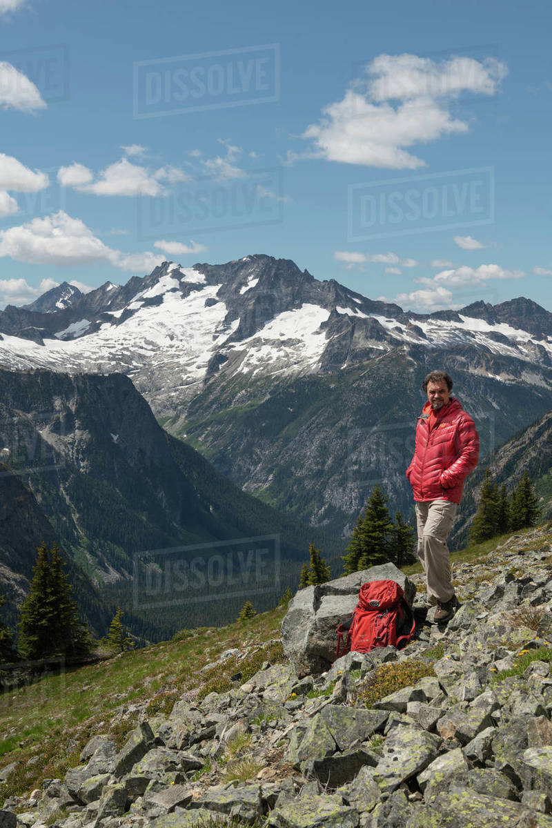 Adult male hiker with red jacket and backpack relaxing on Ragged Ridge ...