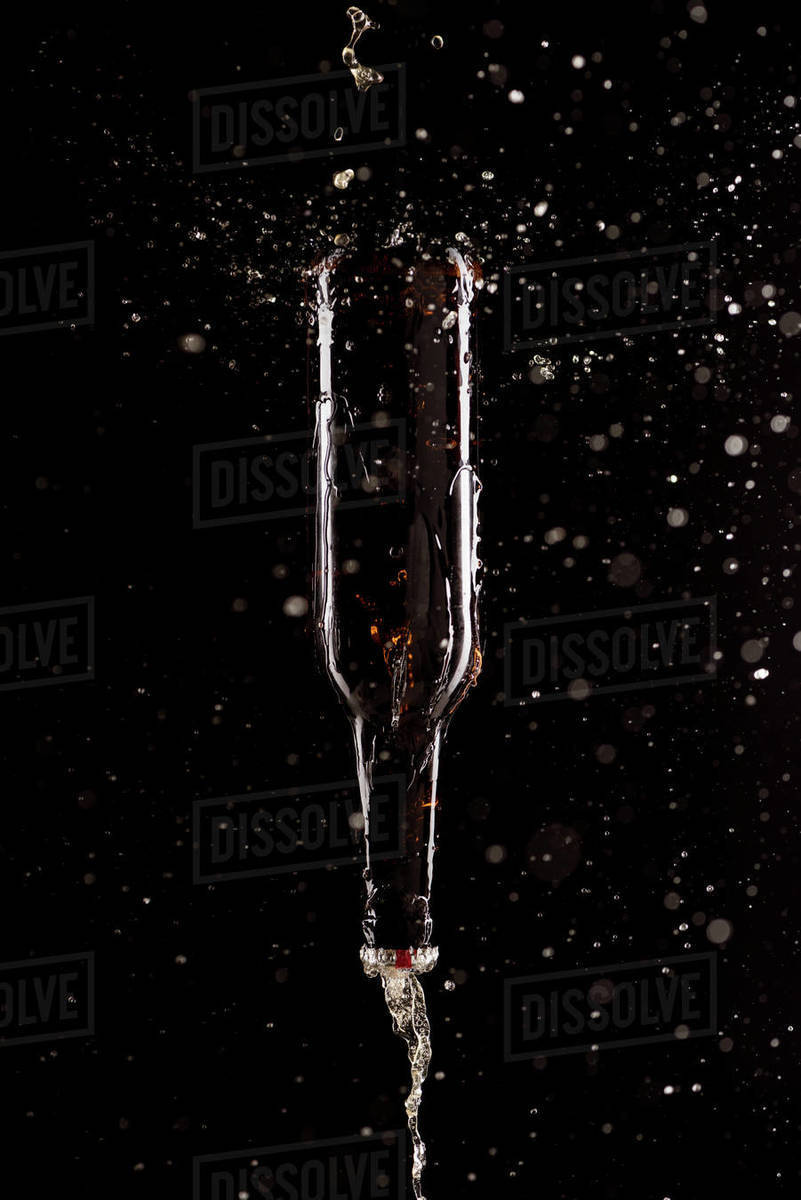 Beer with splashes and bottle upside down falling isolated on black