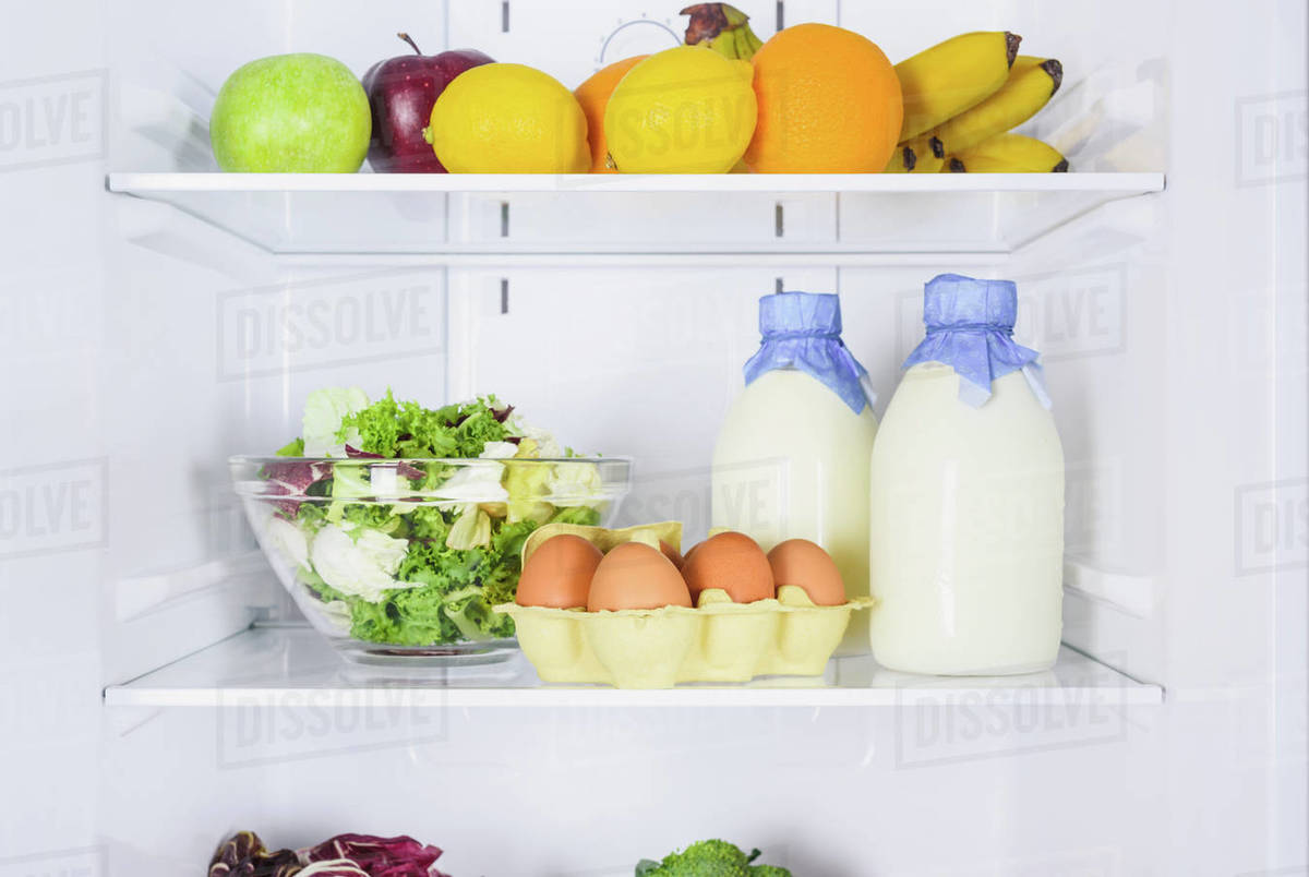 Oranges, apples, eggs and milk in bottles in fridge Stock Photo Dissolve