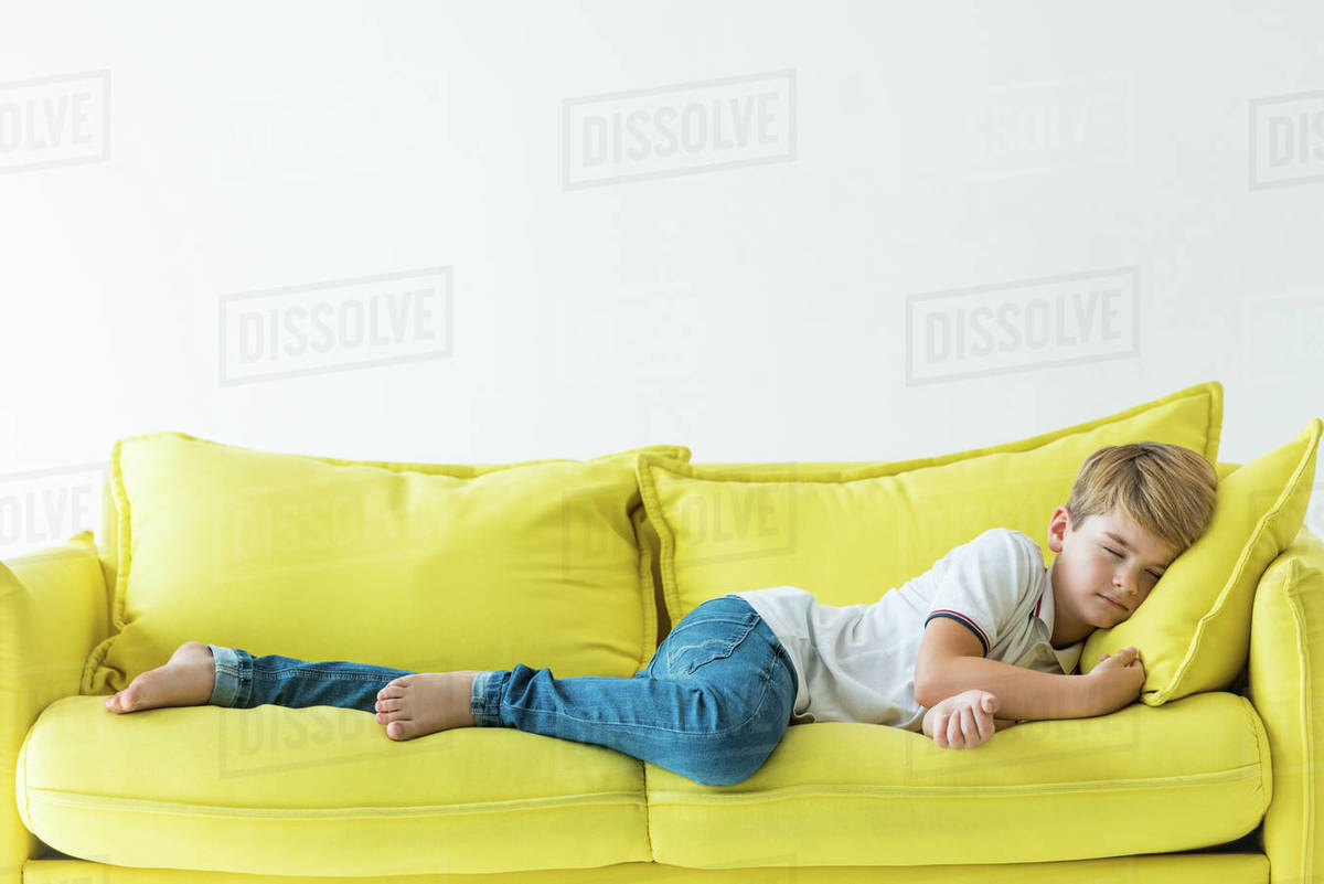 Adorable boy sleeping on yellow sofa isolated on white Stock Photo