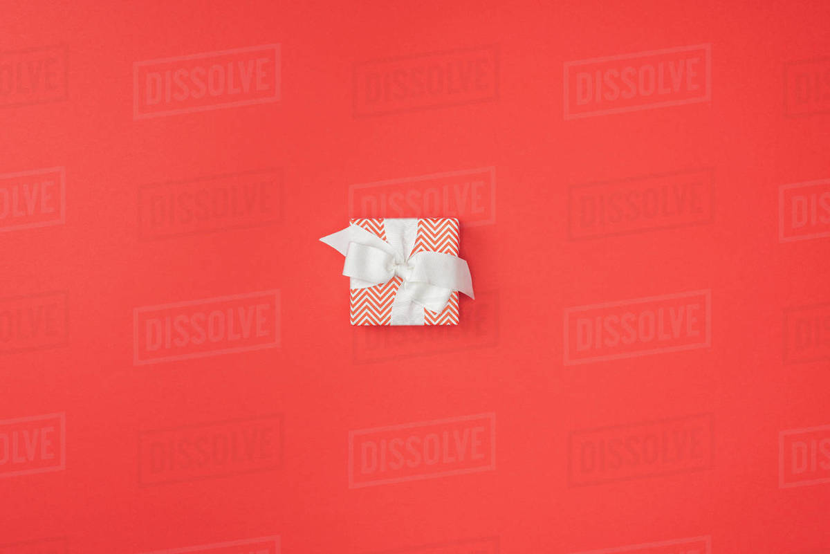 top view of wrapped christmas gift with white ribbon isolated on red