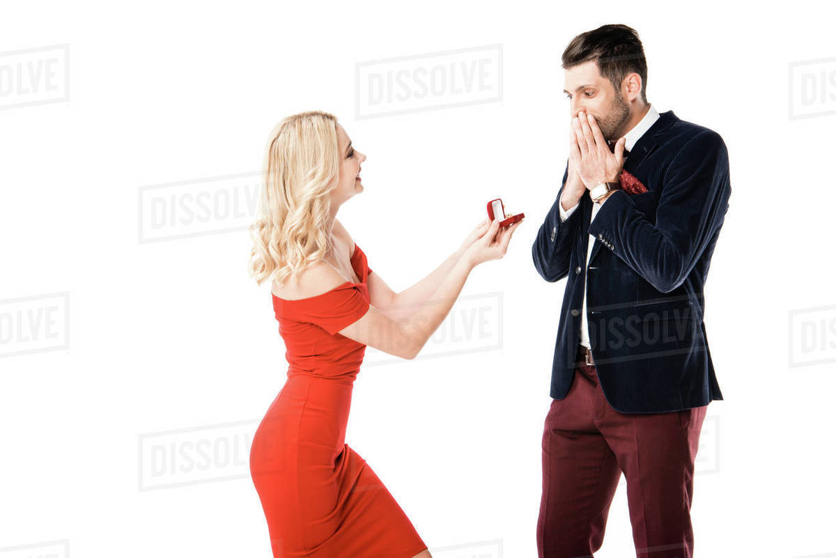 Attractive woman proposing surprised boyfriend with ring isolated on