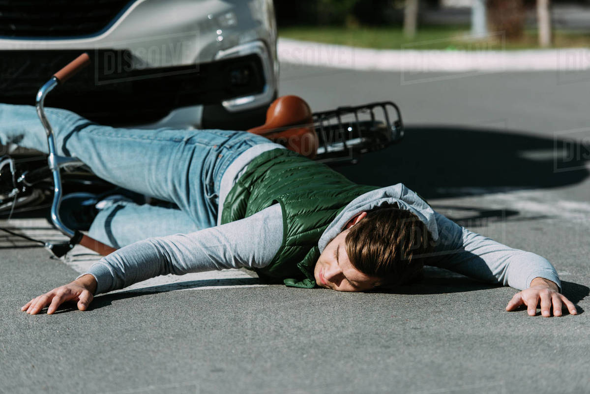 Male bicycle rider hit by car on road, car accident concept Stock