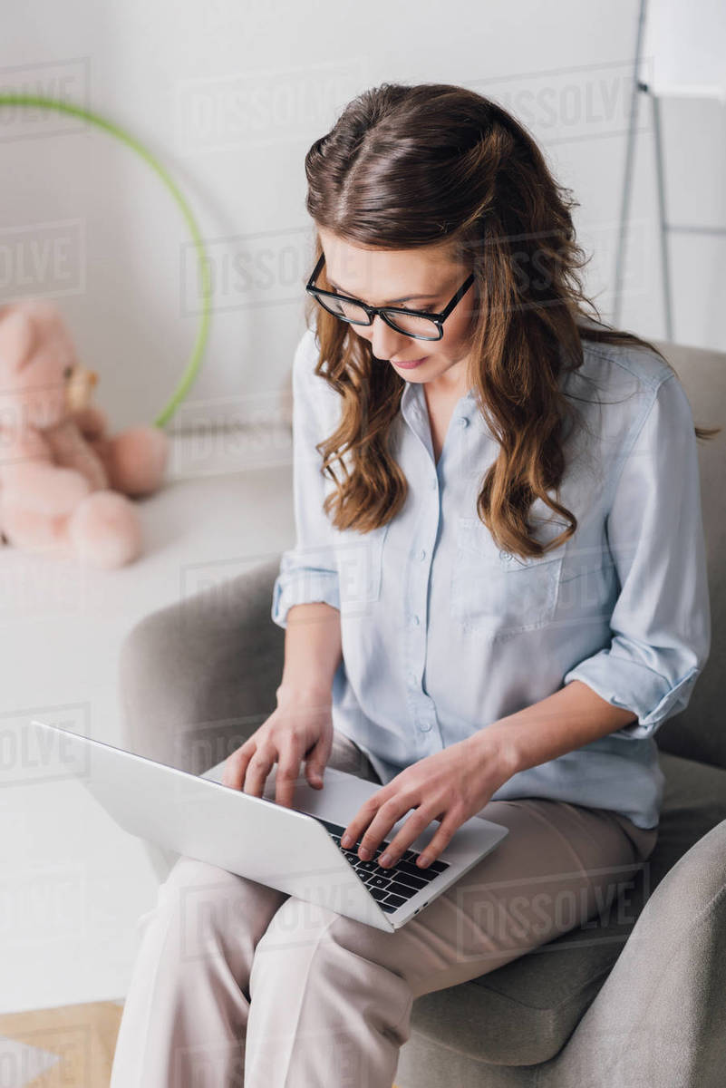 High angle view of child psychologist sitting in armchair and working