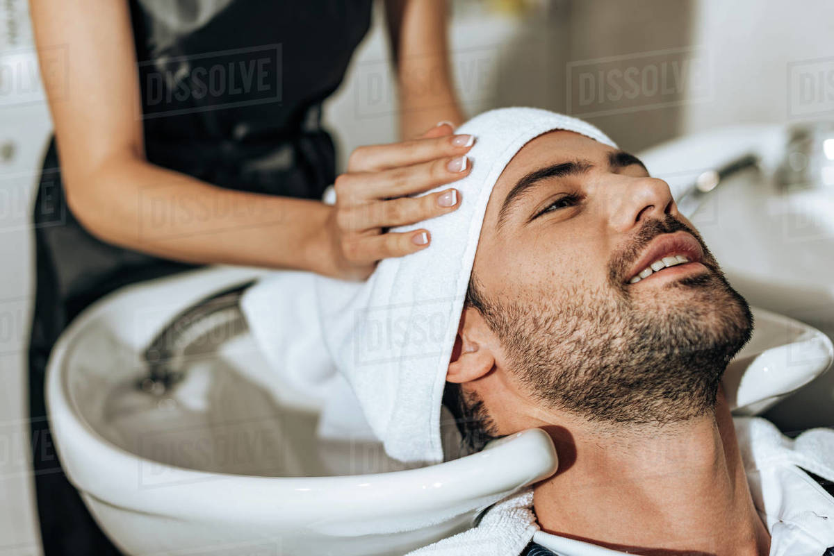 Partial View Of Hairdresser Washing Hair To Smiling Handsome Man