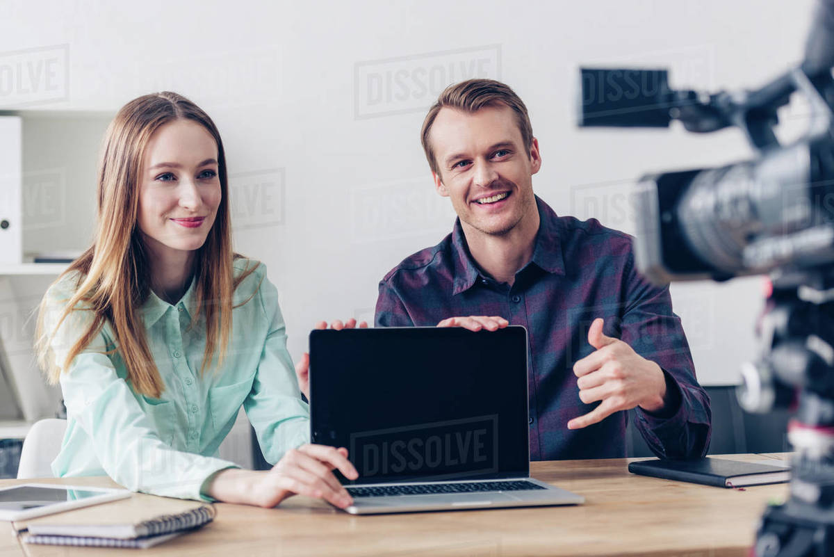 Happy video bloggers recording vlog and pointing on laptop with blank ...